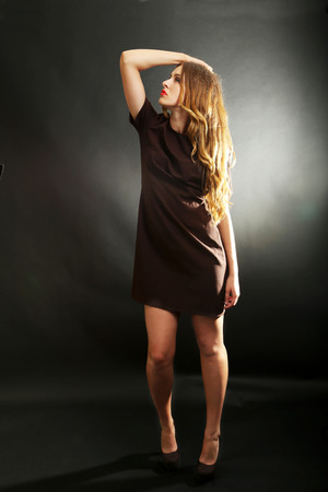 Young beautiful girl in brown dress on black backgroundの写真素材
