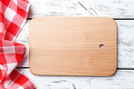 Empty wooden table with cutting board and napkin on white background