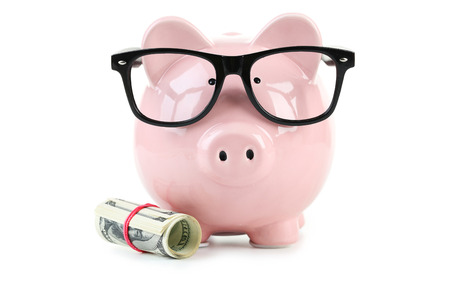 Pink piggy bank with glasses and dollars isolated on a whiteの写真素材