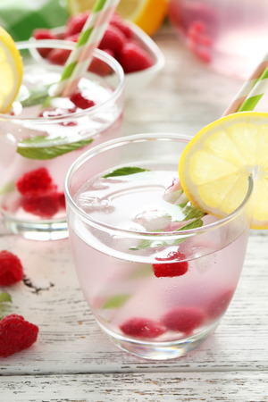 Raspberries and juice in glass on white wooden backgroundの写真素材