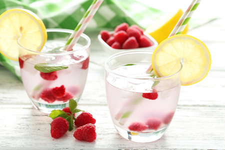 Raspberries and juice in glass on white wooden backgroundの写真素材