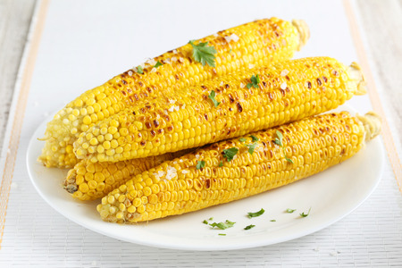 Fresh tasty grilled corn on white plateの写真素材
