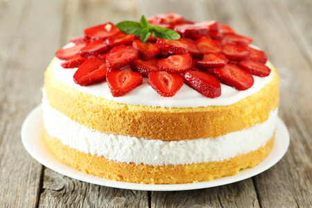 Sweet cake with strawberries on plate on grey wooden backgroundの写真素材