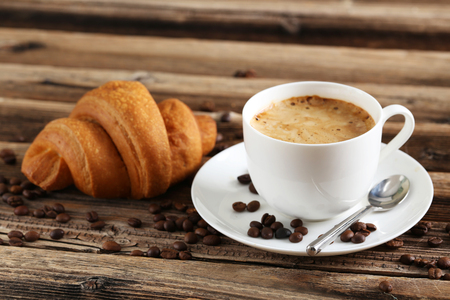Delicious croissant with cup of coffee on brown wooden backgroundの写真素材