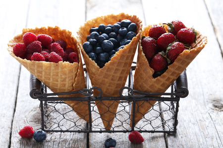 Waffle cones with berries on wooden tableの写真素材