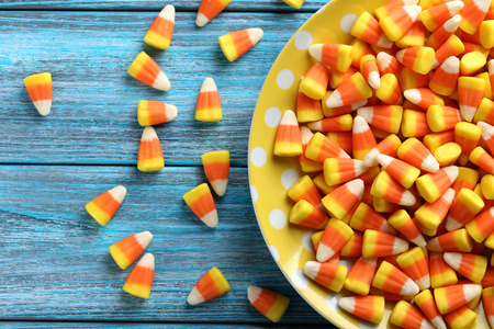 Halloween candy corns in plate on blue wooden background