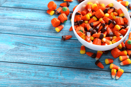 Halloween candy corns in bowl on blue wooden background
