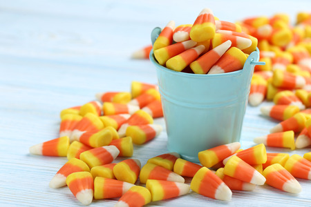 Halloween candy corns in bucket on blue wooden backgroundの写真素材