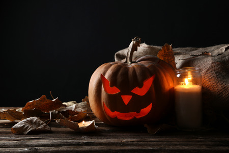 Halloween pumpkin with candle on brown wooden tableの写真素材