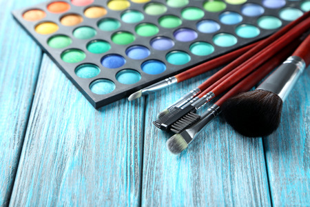Makeup brushes and cosmetics on blue wooden table