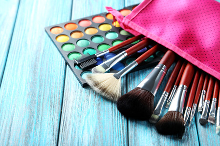 Makeup brushes and cosmetics on blue wooden tableの写真素材