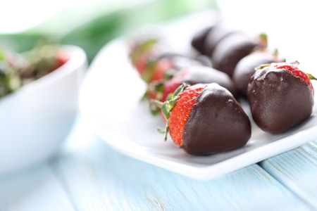 Fresh strawberries dipped in dark chocolate on blue wooden backgroundの写真素材