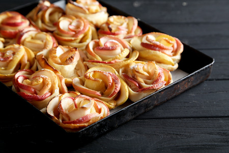 Fresh puff pastry with apple shaped roses on black wooden tableの写真素材