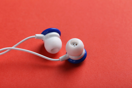 White headphones on a red paper background