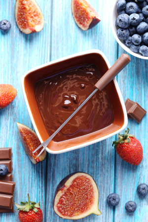 Chocolate fondue with fresh berries on a blue wooden tableの写真素材