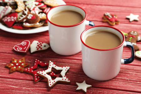 Christmas cookies with cup of hot coffee on a red wooden tableの写真素材