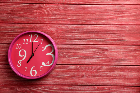Pink round clock on a red wooden table
