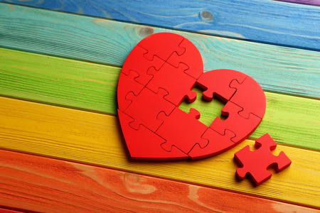 Red puzzle heart on colorful wooden backgroundの写真素材