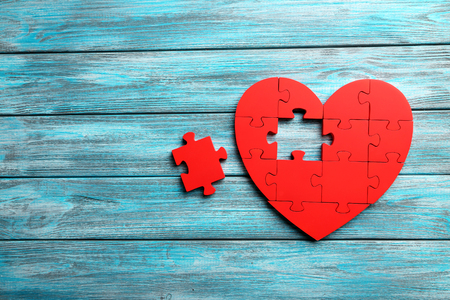 Red puzzle heart on blue wooden backgroundの写真素材