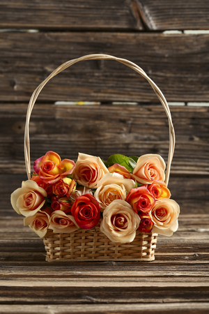 Bouquet of orange roses in basket on brown wooden backgroundの写真素材