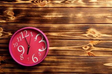 Pink round clock on a brown wooden tableの写真素材