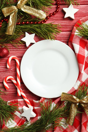 Christmax tree branch with baubles, candies on red wooden tableの写真素材