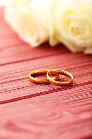 Golden wedding rings on a red wooden tableの写真素材