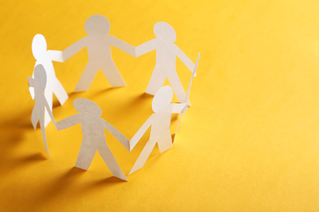 Paper people on the orange paper backgroundの写真素材