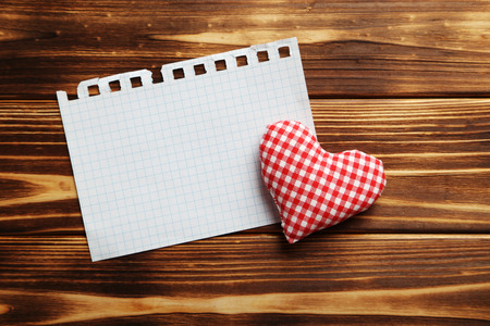 Love heart and sheet of blank paper on a brown wooden tableの写真素材