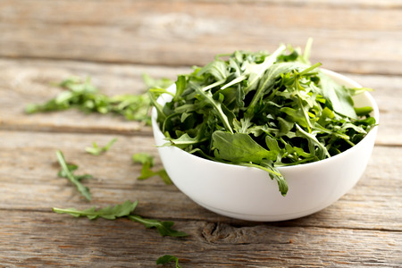 Fresh arugula leafs on a grey wooden table