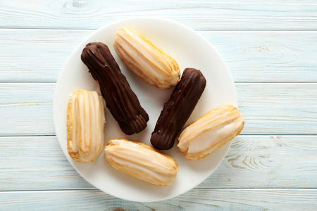Sweet eclairs on a white wooden table