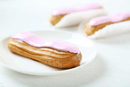 Eclairs with glaze on a white wooden tableの写真素材