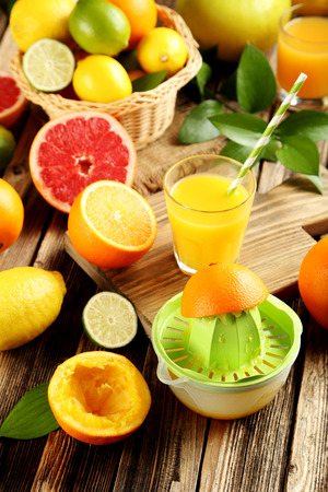 Citrus fruits with juicer on a brown wooden tableの写真素材
