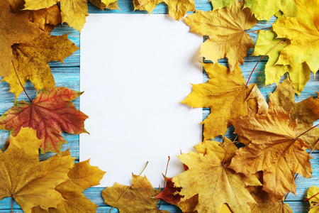 Autumn leaf with blank sheet on a blue wooden table