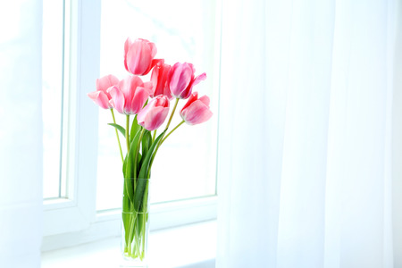 Pink tulips in vase on the windowsillの写真素材