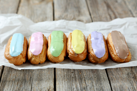 Eclairs with glaze on a grey wooden table