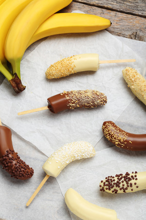 Banana covered in chocolate on a pergamentの写真素材