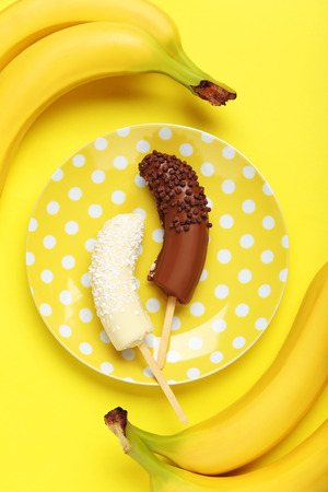 Banana covered in chocolate on a yellow backgroundの写真素材