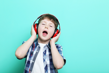 Portrait of young boy with headphones on mint backgroundの写真素材