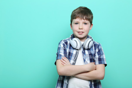 Portrait of young boy with headphones on mint background