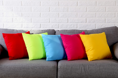 Colorful pillows on grey sofa on a brick wall backgroundの写真素材