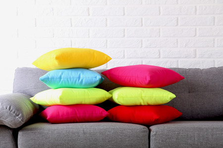 Colorful pillows on grey sofa on a brick wall backgroundの写真素材