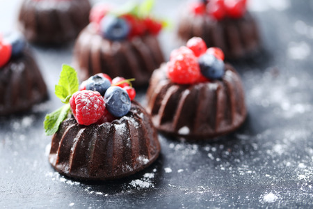 Sweet chocolate cakes with berries on black wooden tableの写真素材