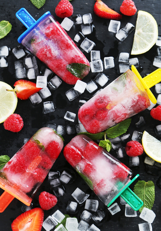 Popsicles with berries on black wooden tableの写真素材
