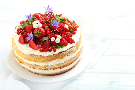 Delicious biscuit cake with berries on blue wooden tableの写真素材