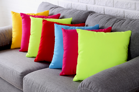 Colorful pillows on grey sofa on a brick wall background