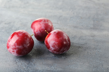 Fresh plums on a grey wooden tableの写真素材