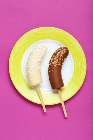 Banana covered in chocolate on a pink backgroundの写真素材
