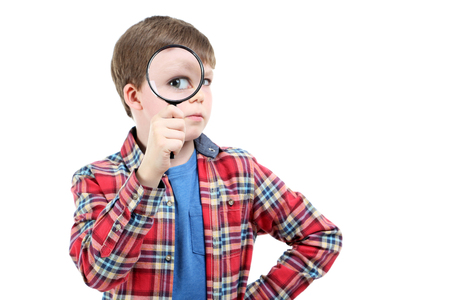 Young boy with magnifying glass on a white backgroundの写真素材