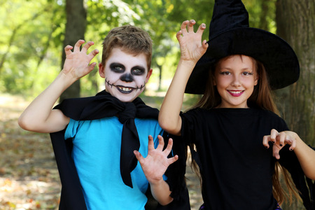 Beautiful girl witch and little boy in the park, outdoorsの写真素材